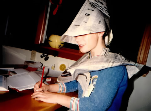 A young Justin in pajamas, sporting a self-made newspaper hat, is busy drawing at the kitchen table.